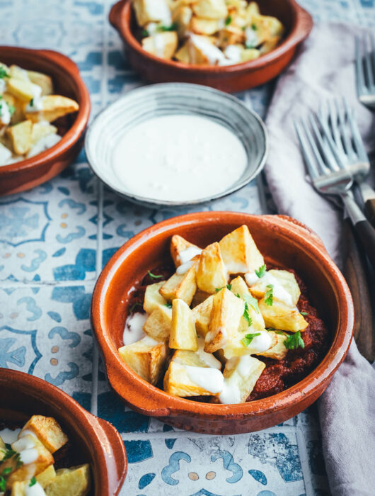 Wenn ich an spanische Tapas denke, denke ich zuerst an Patatas Bravas! Knusprig frittierte Kartoffeln mit einer scharfen roten Sauce und einer würzigen weißen Sauce. Schon als Kind habe ich sie geliebt. Jetzt habe ich mir den Spanien-Urlaub nach Hause geholt und bereite meine Patatas Bravas einfach im Air Fryer zu. Das geht super schnell und unkompliziert! So hat man in kürzester Zeit die perfekte Urlaubserinnerung auf dem Tisch stehen. Hier gibt es das köstliche Rezept für Kartoffelwürfel mit scharfer Tomatensauce (Salsa brava) und einer schnellen Knoblauchmayonnaise (Aioli)! | moeyskitchen.com