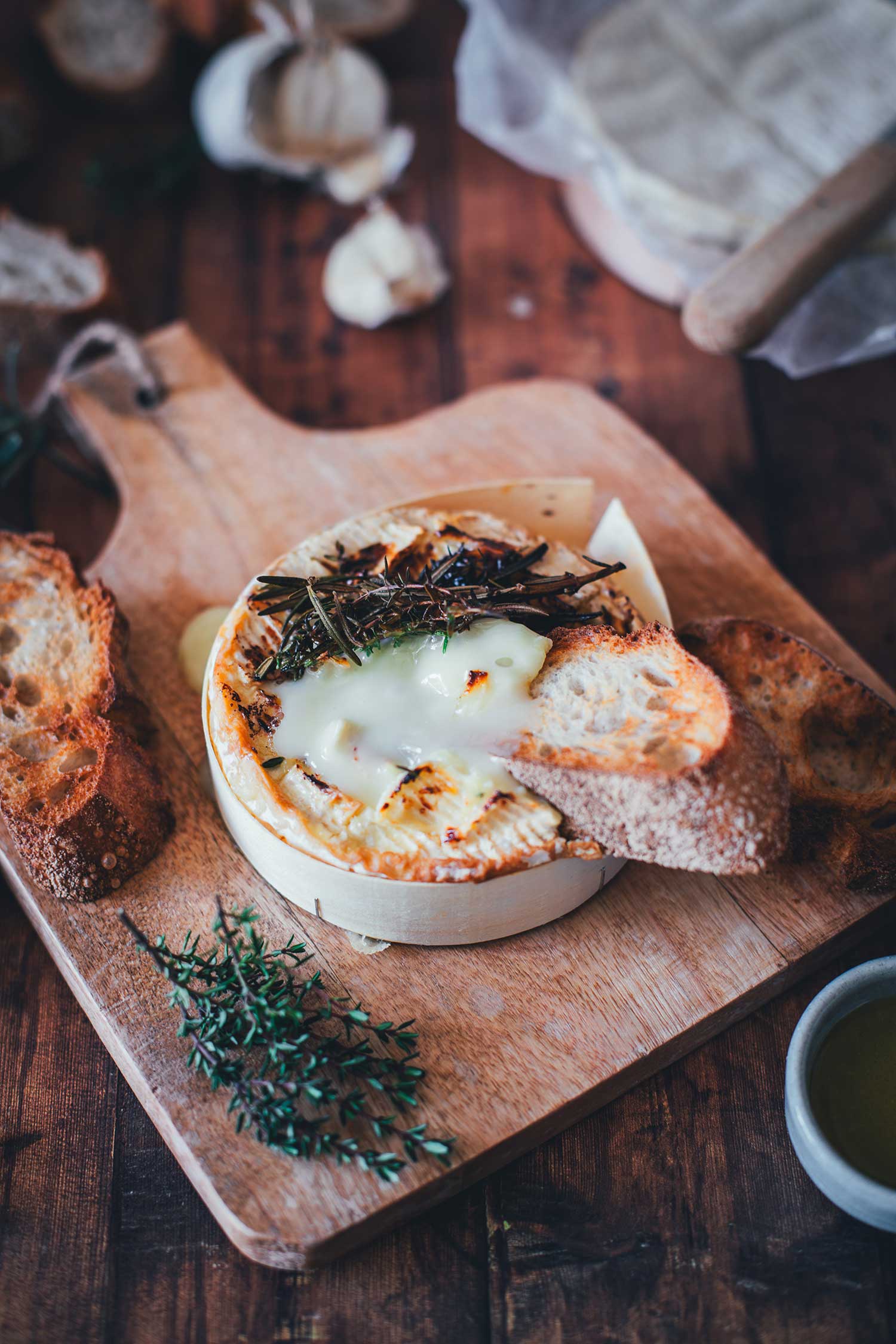 Cremig zerlaufener Camembert als Ofenkäse aus dem Airfryer, in den eine knusprige Scheibe Baguette gedippt wird.
