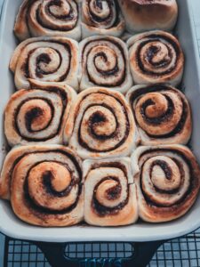 Fertig gebackene Zimtschnecken in einer Backform kommen goldbraun aus dem Ofen.
