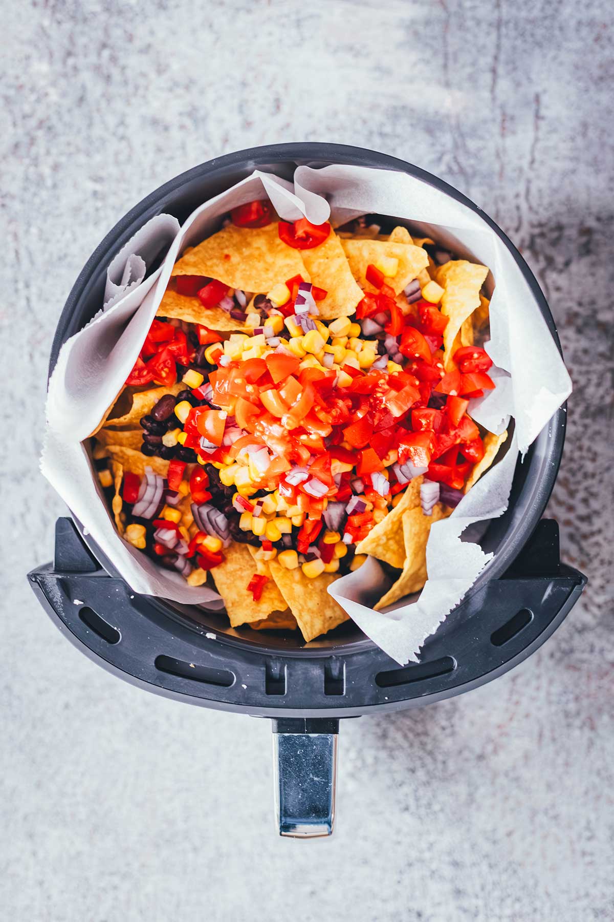 Loaded Nachos aus der Heißluftfritteuse sind eine blitzschnelle und unkomplizierte Idee für mit Käse und Toppings überbackene Tortilla Chips als Snack. Dafür werden alle Zutaten in den Airfryer geschichtet und zusammen gebacken. Anschließend kann man die Nachos mit Guacamole und Sour Cream servieren. | moeyskitchen.com