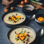 Cremige Kartoffelsuppe mit knusprigem Bacon, geschmolzenem Cheddar und Frühlingszwiebeln in einer dunklen Keramikschale – wärmendes Suppenrezept für Herbst und Winter. | moeyskitchen.com