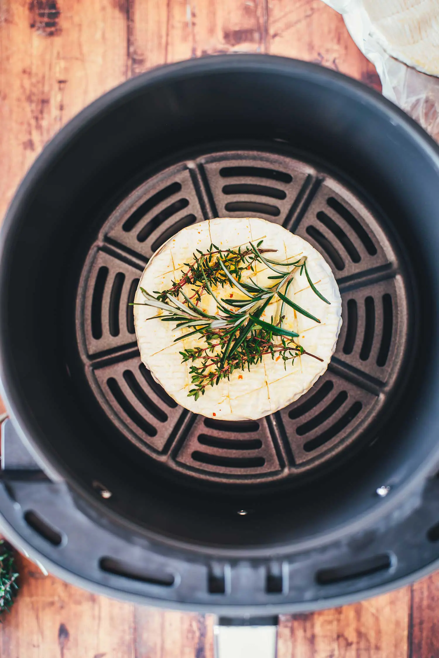 Roher Camembert vor dem Garen in einem runden Airfryer