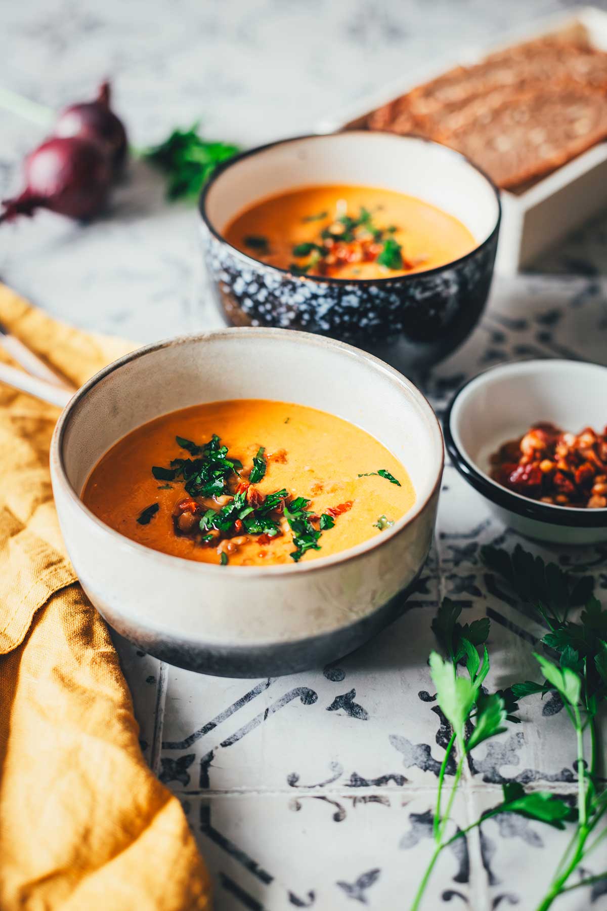 Tomaten-Linsen-Suppe mit Schmand, serviert mit frischen Kräutern und gehackten getrockneten Tomaten. | moeyskitchen.com