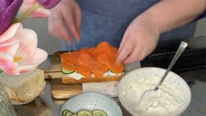 Gurkenscheiben und Räucherlachs werden im nächsten Schritt auf der Frischkäsecreme verteilt