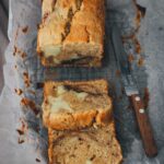 In Stücke geschnittener Apfel-Frischkäse-Kuchen auf Backpapier mit einem Messer | moeyskitchen.com