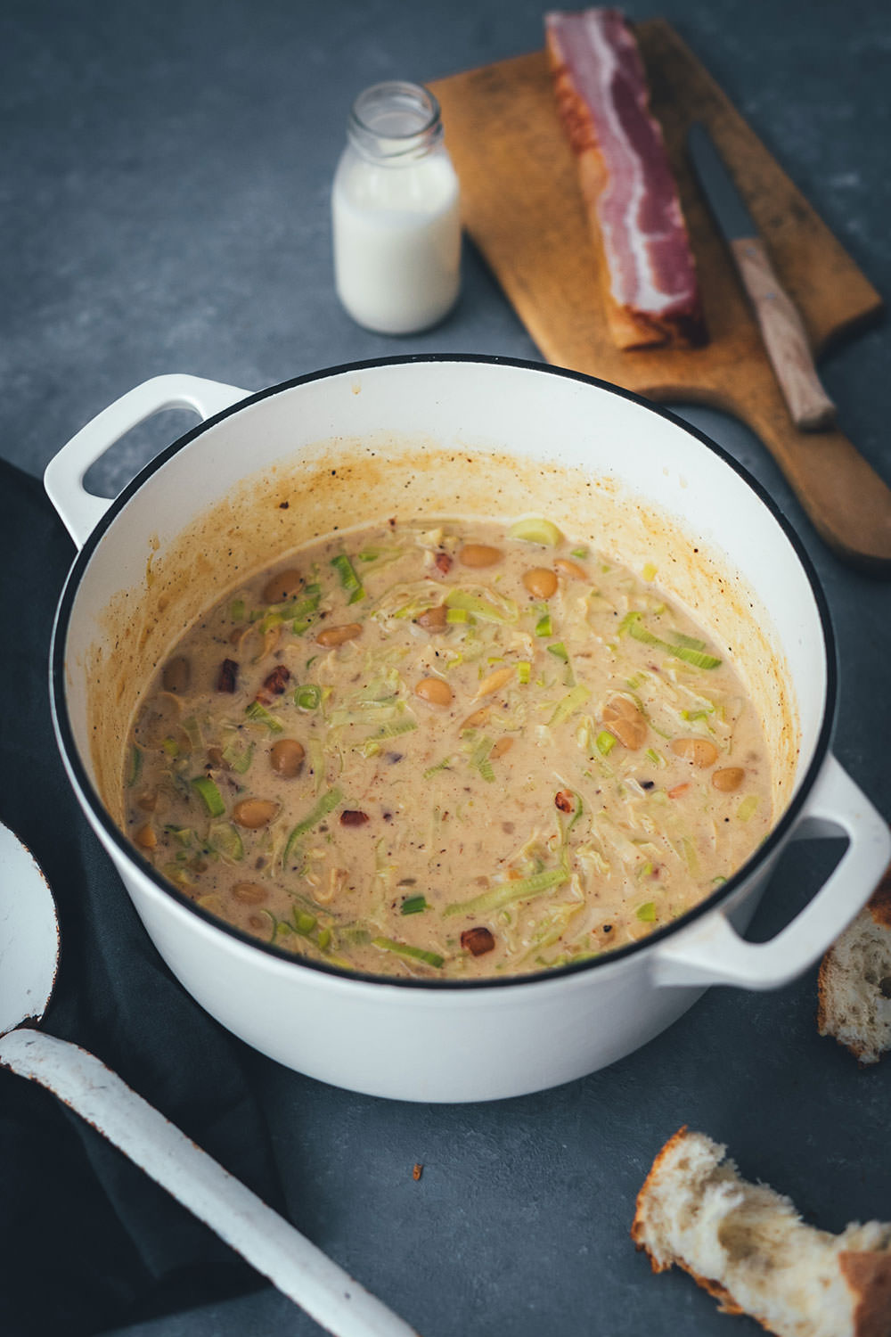 Ein großer gusseiserner Topf, gefüllt mit frisch gekochter Lauch-Suppe, die besonders cremig aussieht. Mit Speck und weißen Bohnen zubereitet das perfekteb Oktober Rezept! | moeyskitchen.com