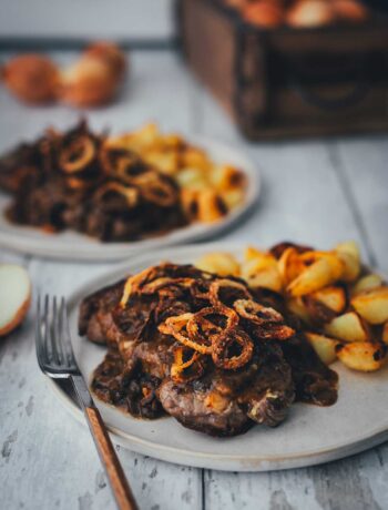 Zwiebelrostbraten mit Sauce, Röstzwiebeln und Bratkartoffeln auf zwei Tellern serviert | moeyskitchen.com