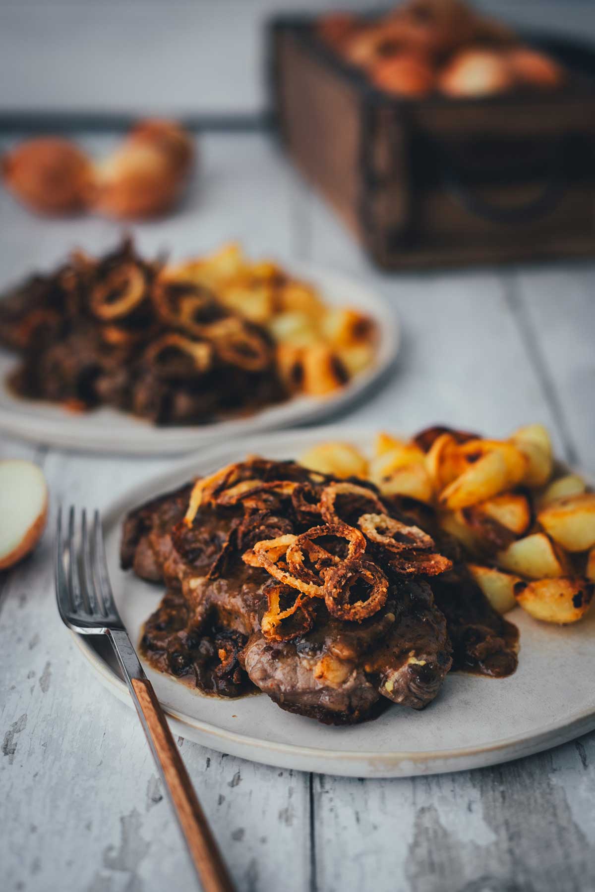 Zwiebelrostbraten mit Sauce, Röstzwiebeln und Bratkartoffeln auf zwei Tellern serviert | moeyskitchen.com