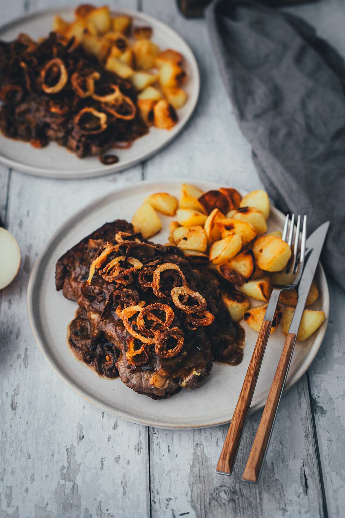 Detailaufnahme von Zwiebelrostbraten mit goldbraunen Röstzwiebeln und Röstkartoffeln | moeyskitchen.com