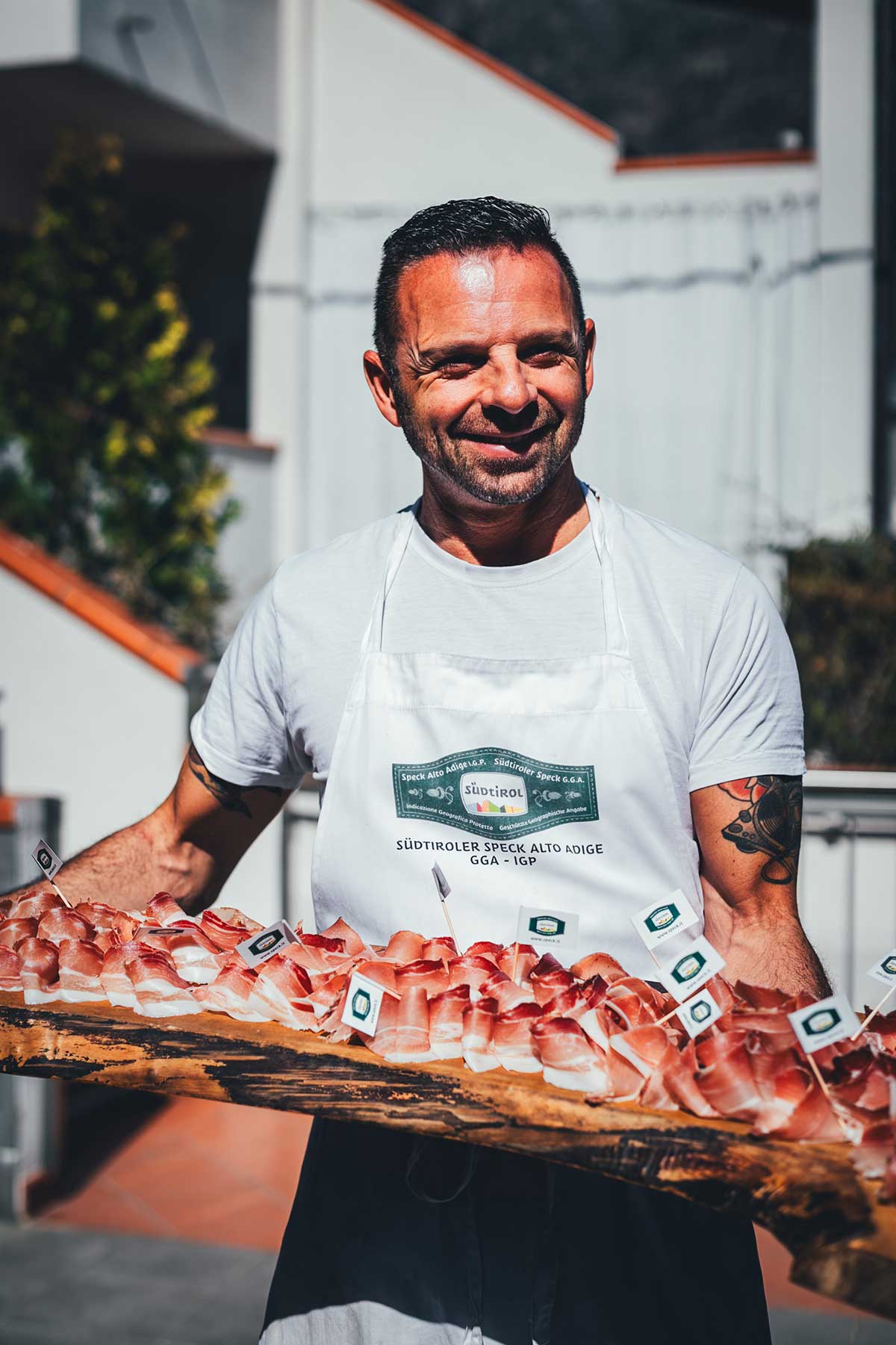 Metzger Schmid aus Südtirol serviert den original Südtiroler Speck aufgeschnitten auf einem Holzbrett in der Sonne für meine Alto Adige Reportage | moeyskitchen.com