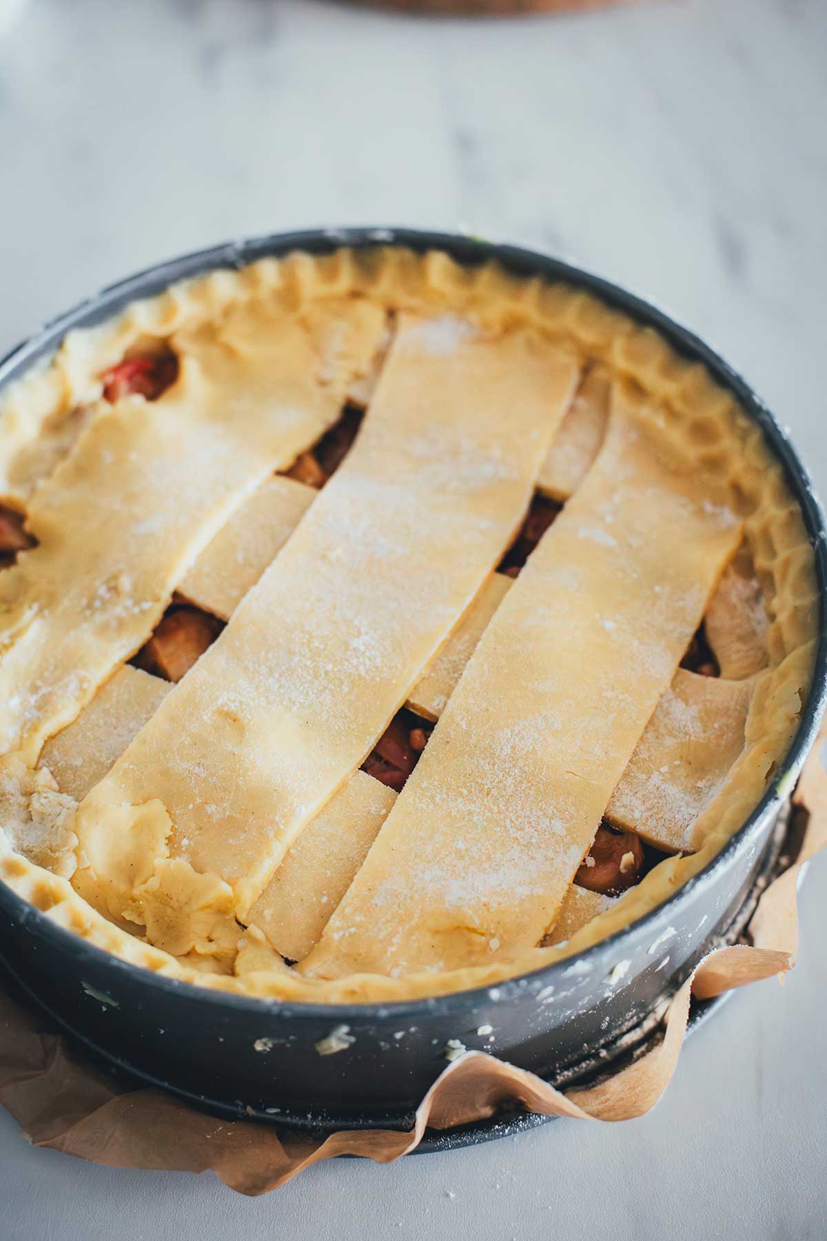 Vorbereiteter Apfelkuchen, bedeckt mit Teigstreifen, auf dem Weg in den Backofe | moeyskitchen.com