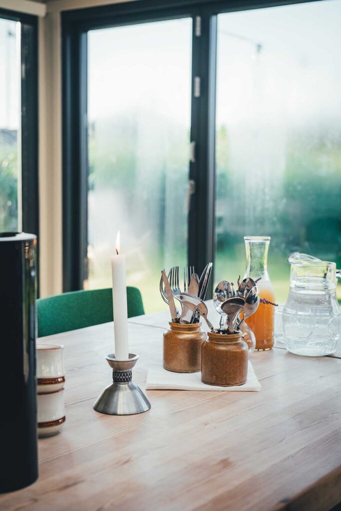 Der Frühstückstisch im Wintergarten von Fjand Badeby mit Kerze, Apdelsaft und Kaffee | moeyskitchen.com