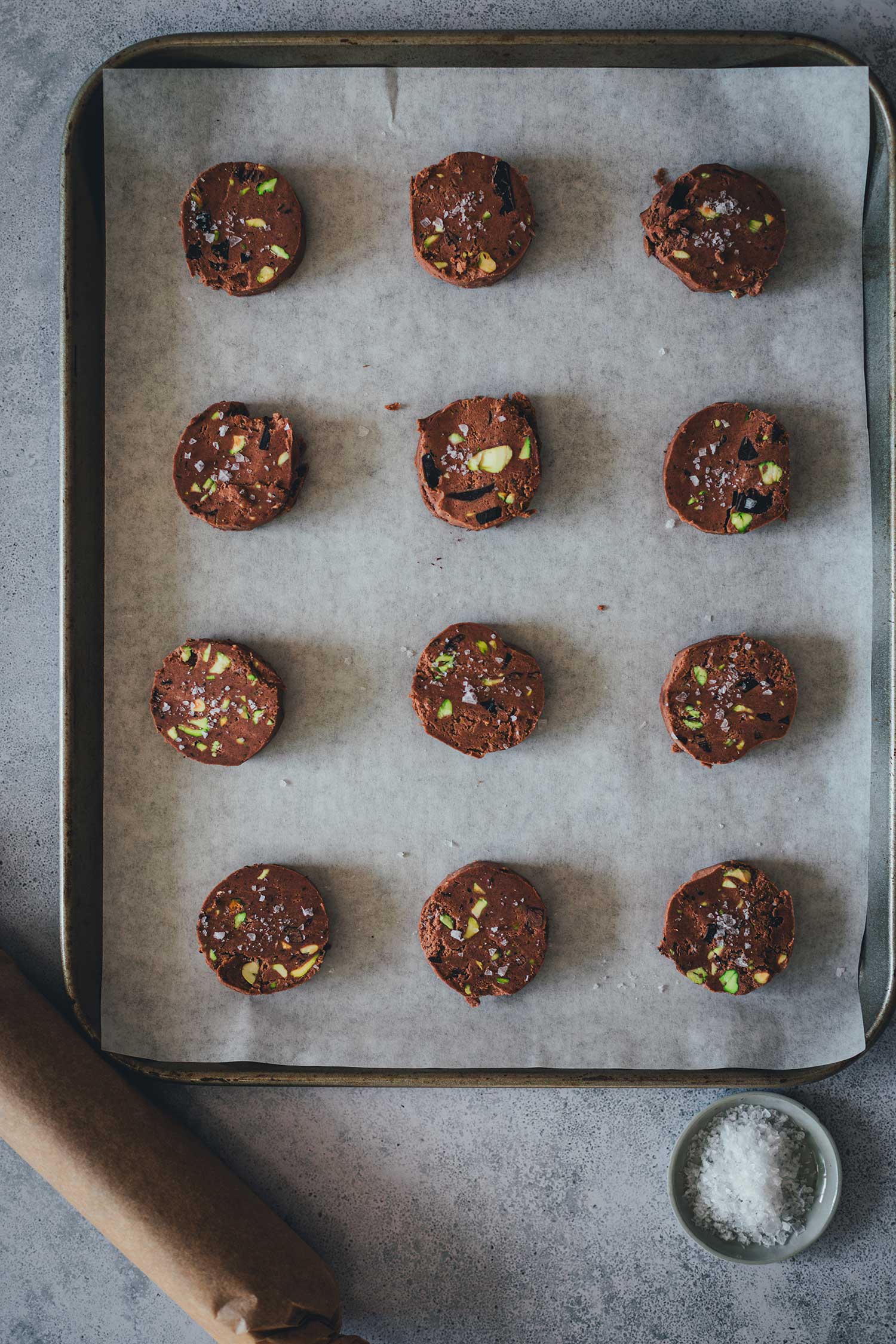 Topshot Aufnahme von rohem Keksteig, in Scheiben geschnitten, auf einem mit Backpapier ausgelegten Backblech