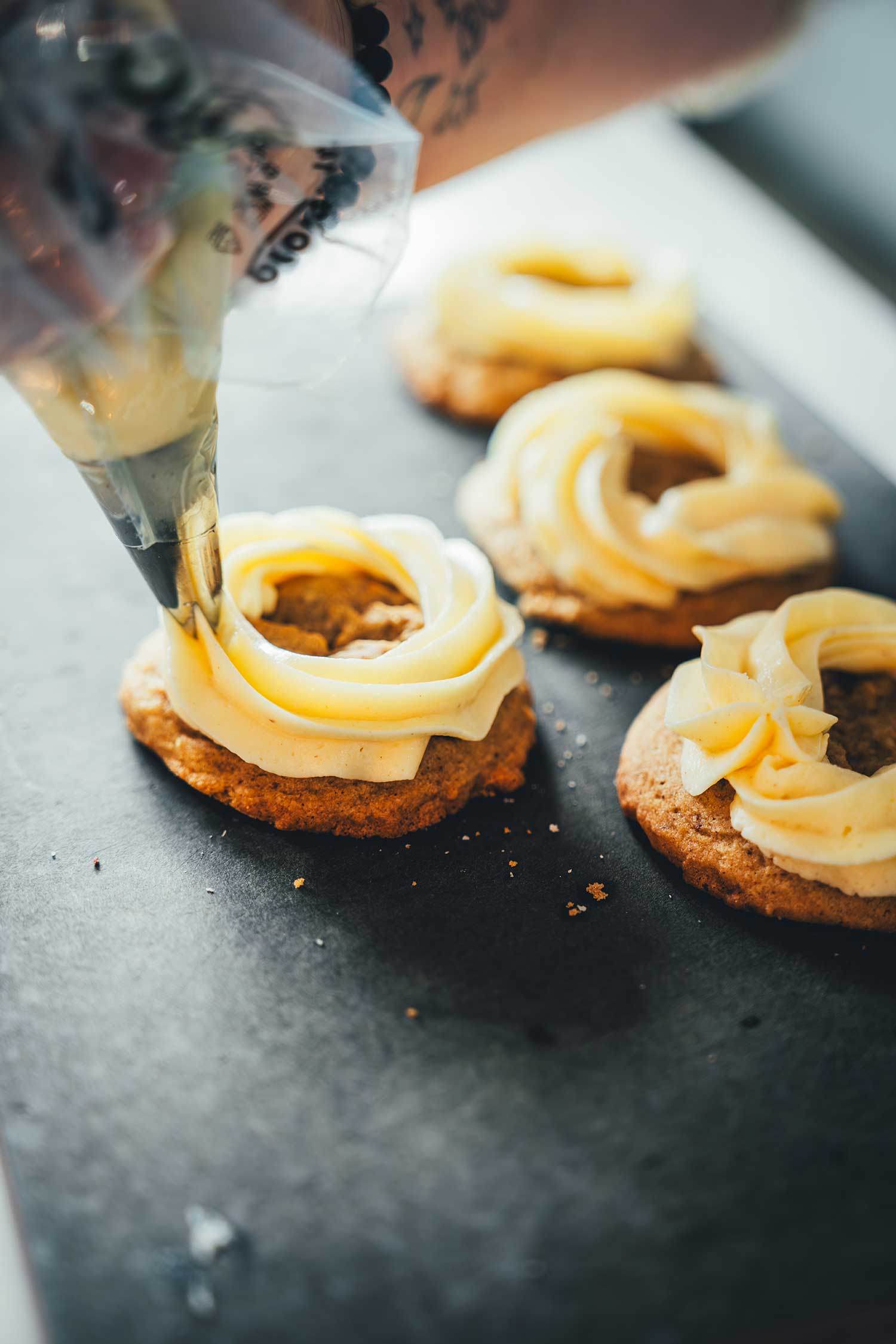 Mascarpone-Frosting wird mit Spritzbeutel und Sterntülle auf einen Cookie aufgespritzt