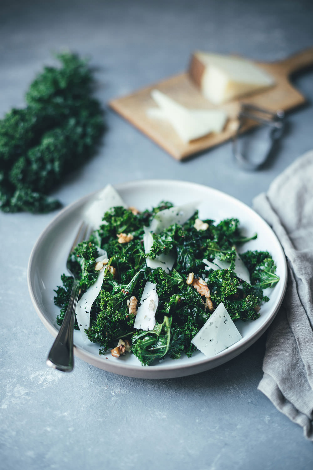 Grünkohl-Salat mit Feigen-Dressing, Manchego und Walnüssen auf hellem Teller, frisch und winterlich angerichtet.