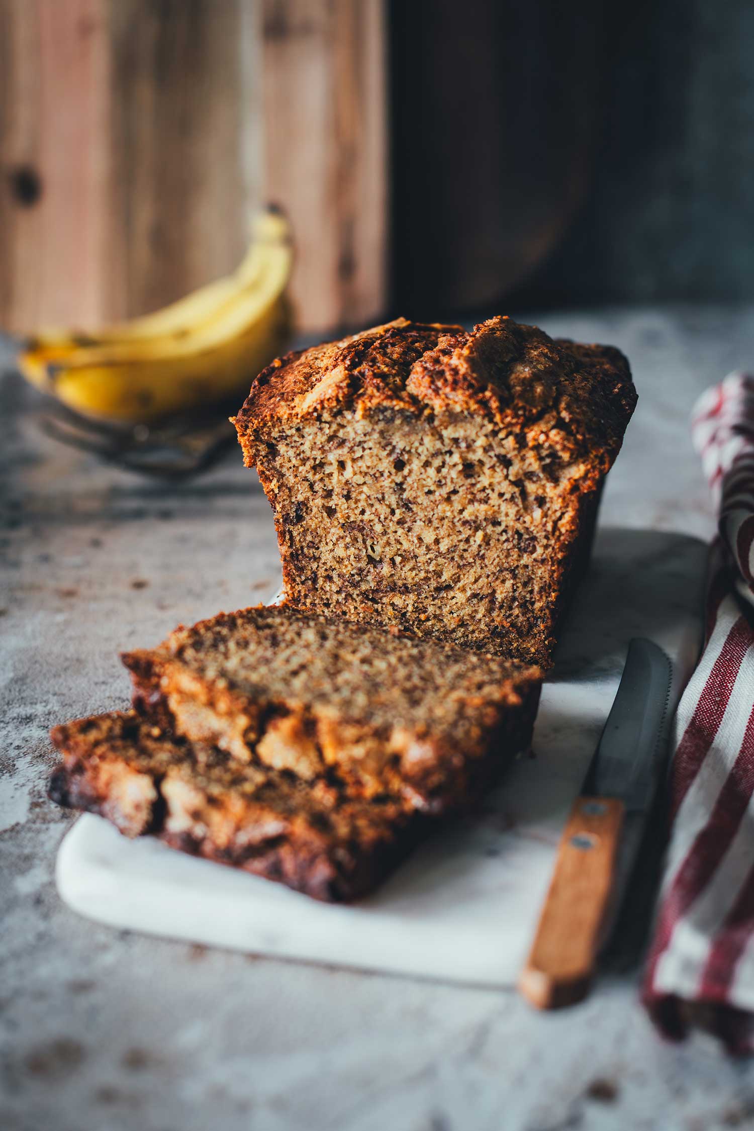 Bananenbrot in Scheiben auf Schneidebrett angerichtet