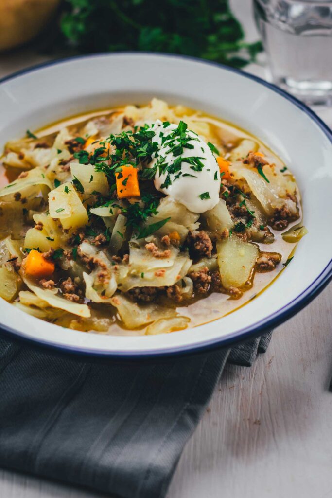 Ein gefüllter Suppenteller mit einem Weißkohl-Eintopf mit Lamm, Kartoffeln und Möhren serviert