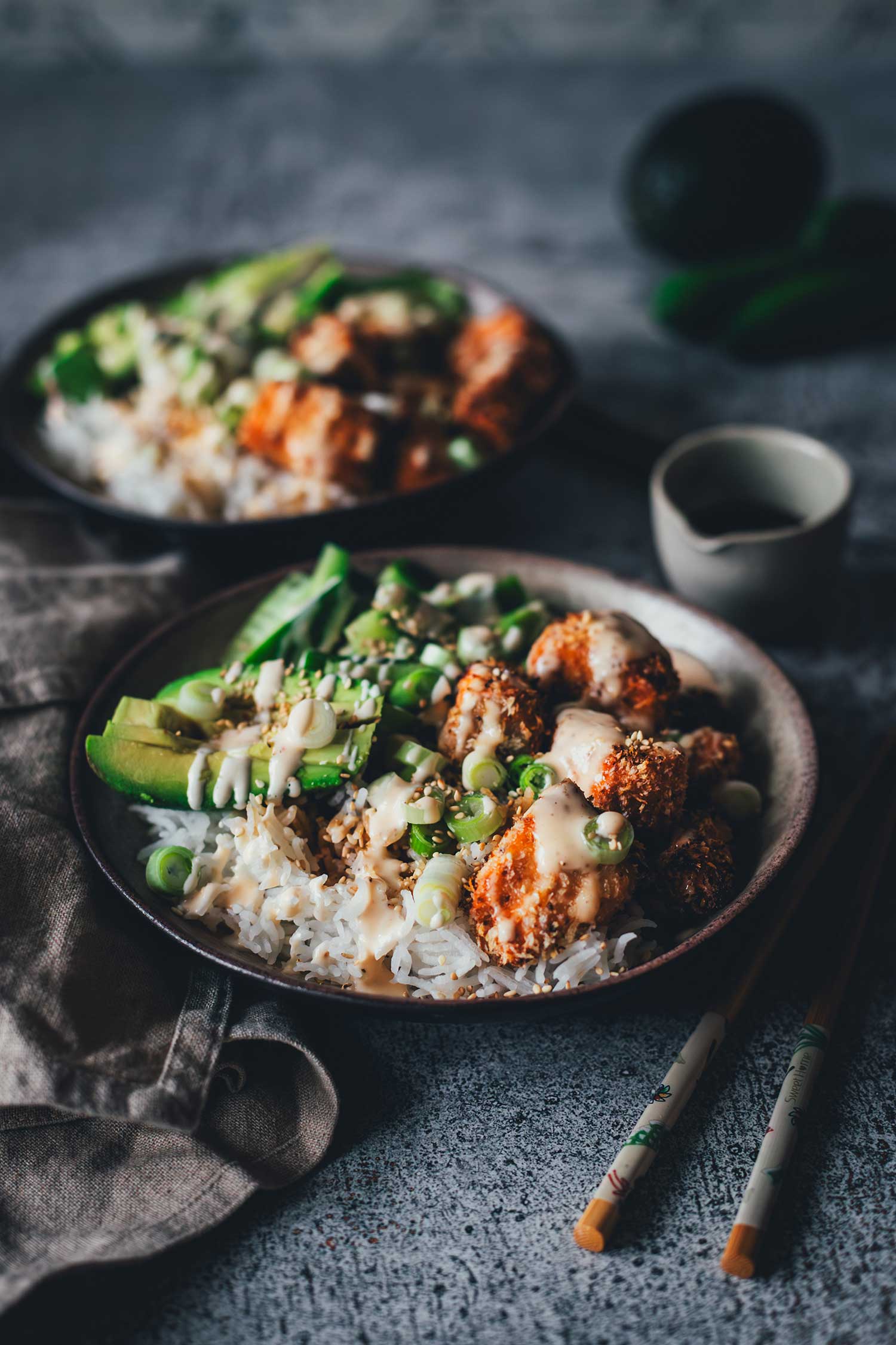 Flache Nahaufnahme einer Crispy Lachs Bowl mit Fokus auf den goldbraun gebackenen Lachswürfeln, cremiger Sauce und Frühlingszwiebeln