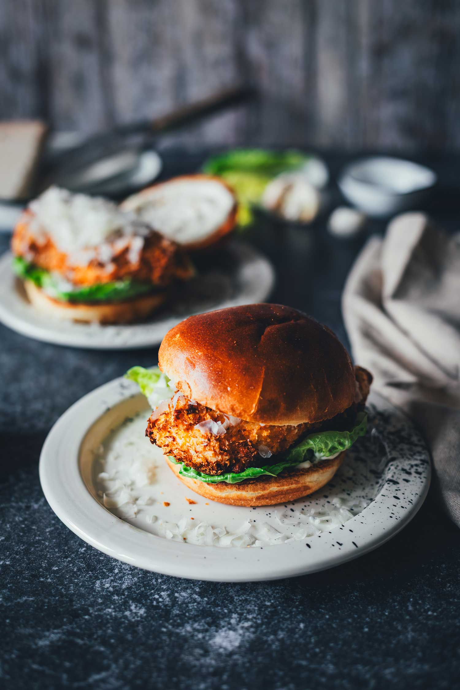Zwei Crispy Chicken Burger mit Caesar-Sauce, knusprig paniertem Hähnchen aus der Heißluftfritteuse und frischem Romanasalat auf gepunkteten Tellern
