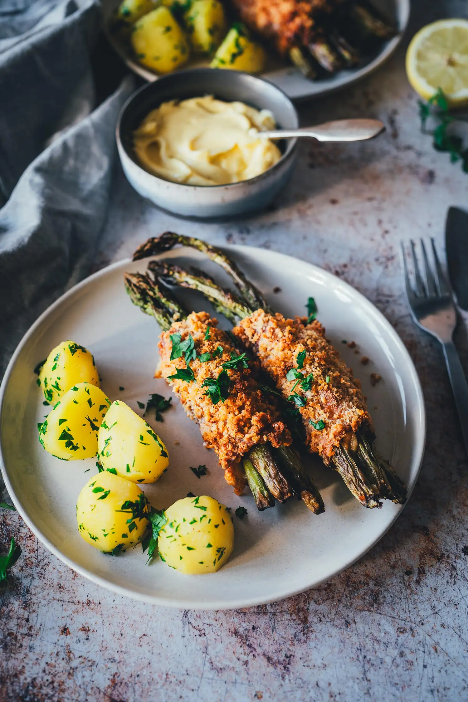 Zwei Teller Spargel Cordon Bleu mit Salzkartoffeln, Hollandaise-Bowl und halbierter Zitrone