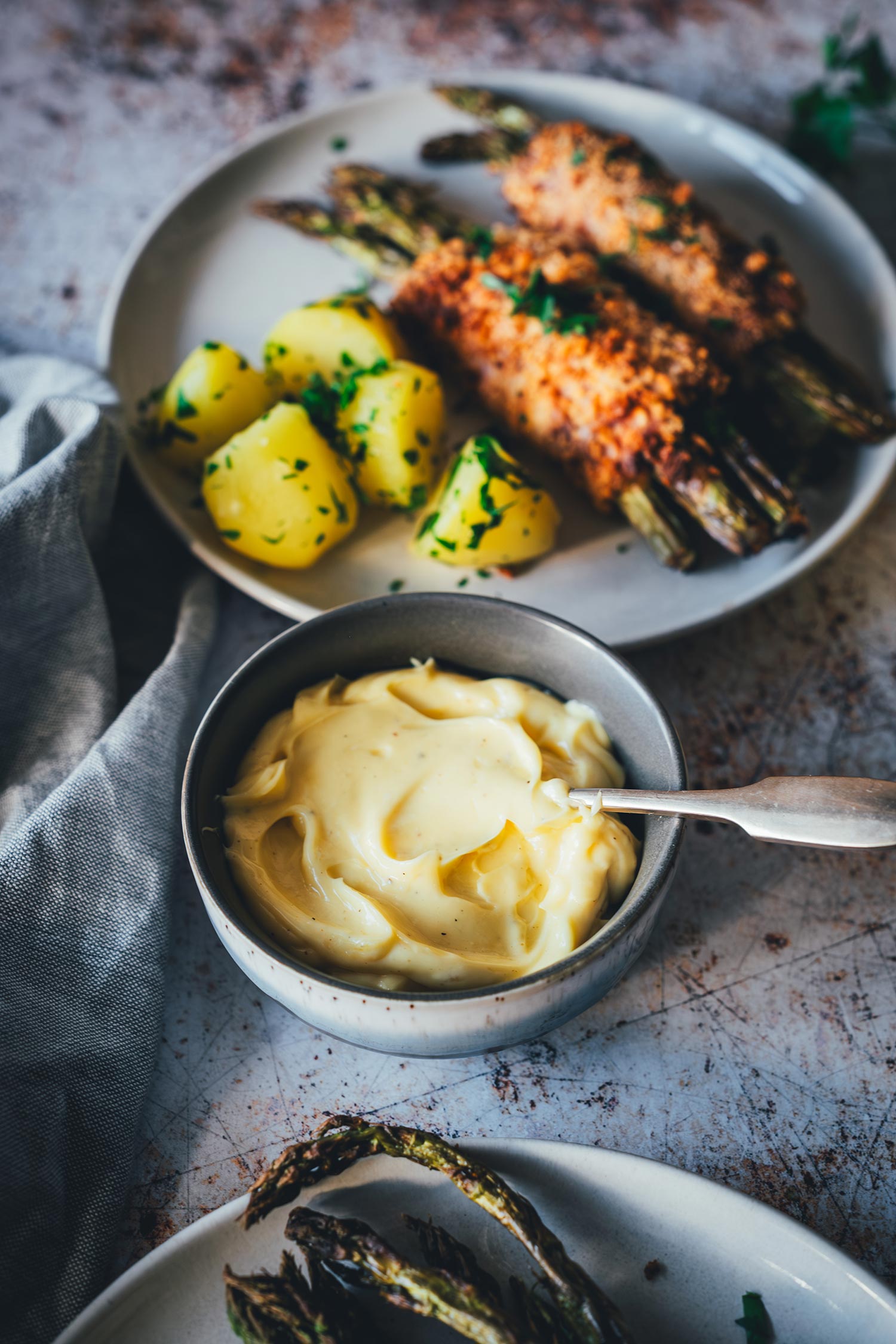 Selbstgemachte Hollandaise in einer Schale neben Teller mit Spargel Cordon Bleu und Salzkartoffeln