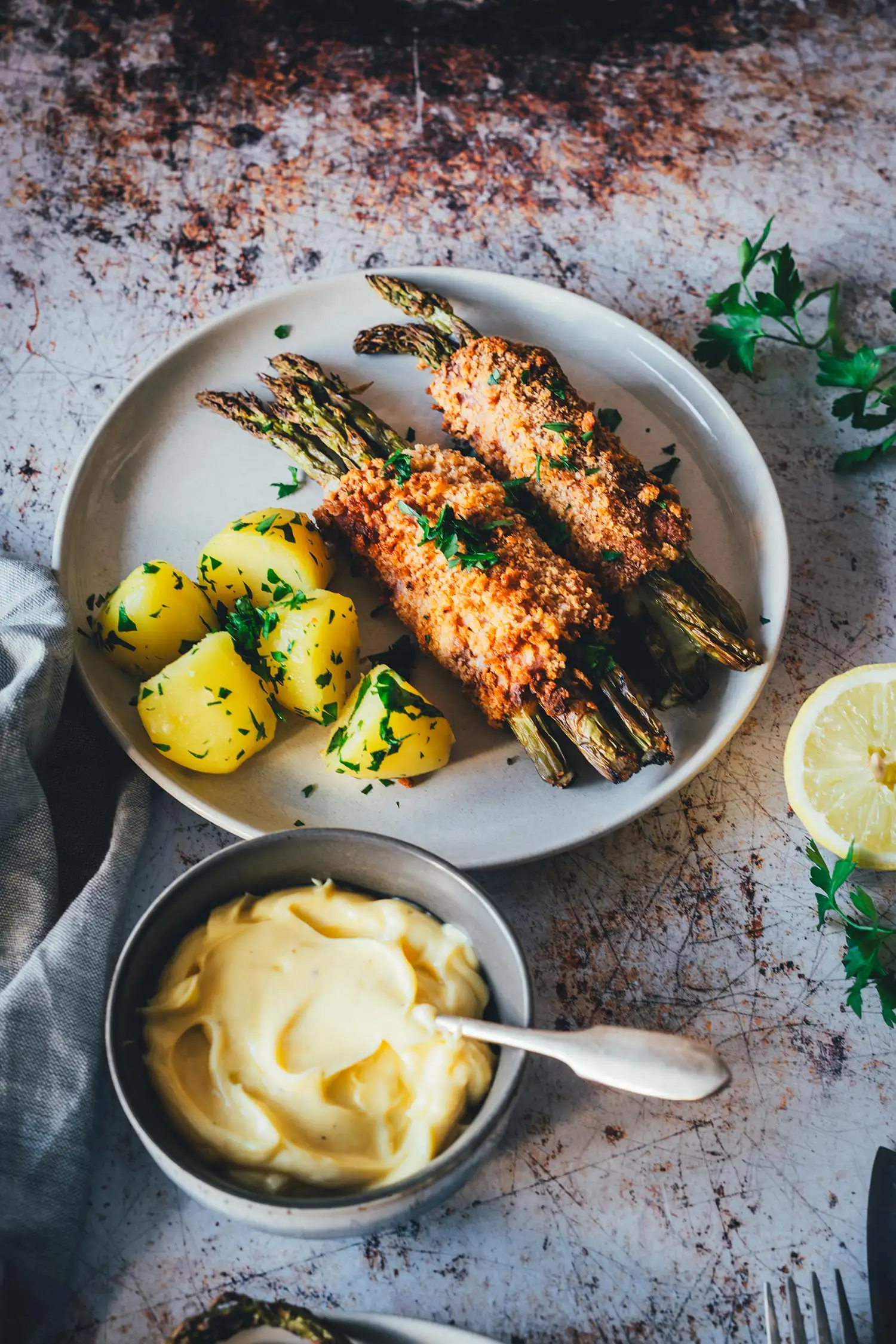 Spargel Cordon Bleu mit Salzkartoffeln, daneben Schale mit cremiger Hollandaise und Zitrone