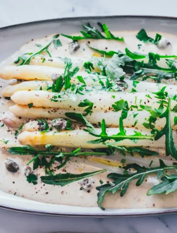 Spargel Tonnato mit weißem Spargel auf cremiger italienischer Thunfischsauce, garniert mit Rucola, Kapern und Petersilie auf ovaler Servierplatte