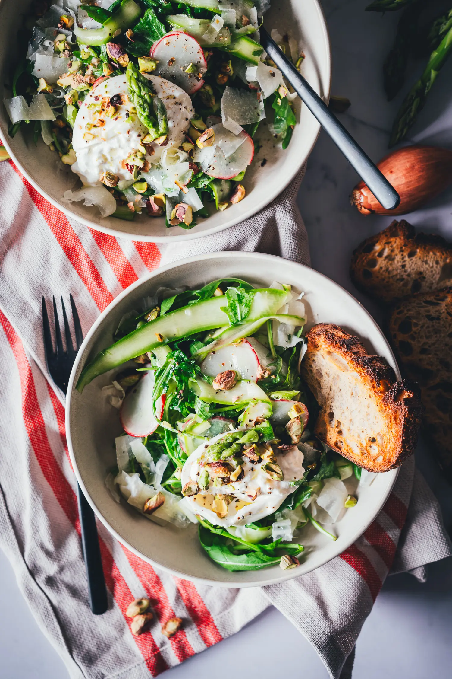 Spargelsalat mit aufgeschnittener cremiger Burrata und Pistazien, daneben getoastetes Sauerteigbrot