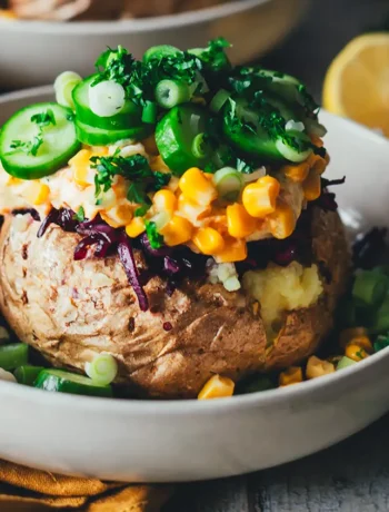Kumpir-Backkartoffel aus dem Airfryer, getoppt mit Möhren-Joghurt, Mais, Gurkenscheiben und Rotkohlsalat, serviert in einer hellen Schale