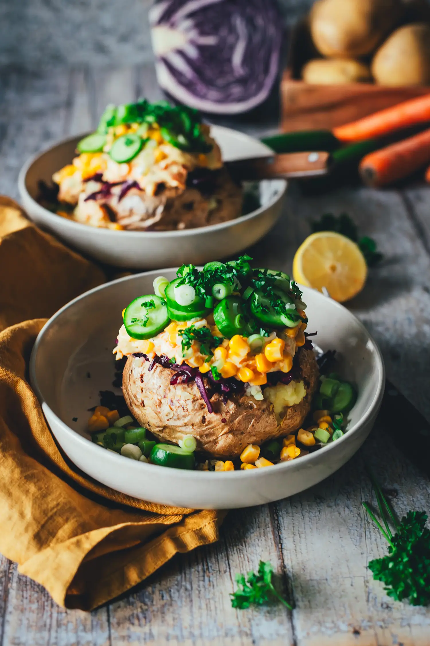 Zwei Portionen Kumpir-Style Backkartoffeln in Schalen mit frischem Gemüse und Petersilie