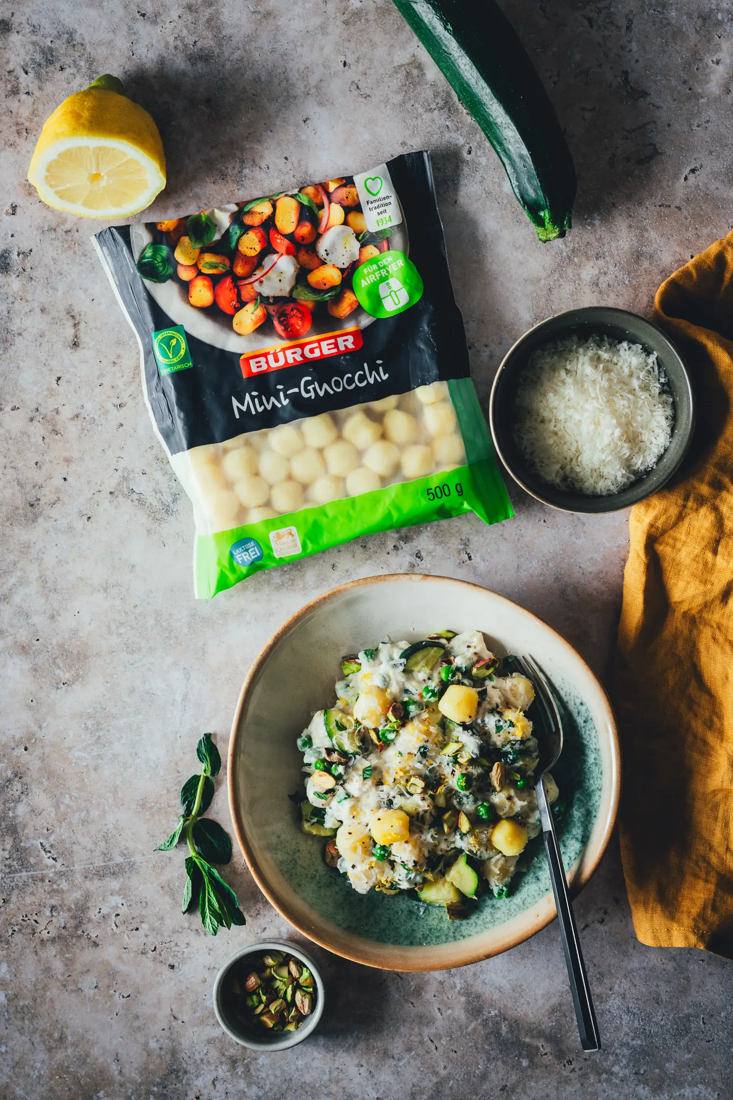 Zwei Bowls Lemon Ricotta Gnocchi mit Zucchini und Erbsen, serviert mit extra Parmesan und Zitrone