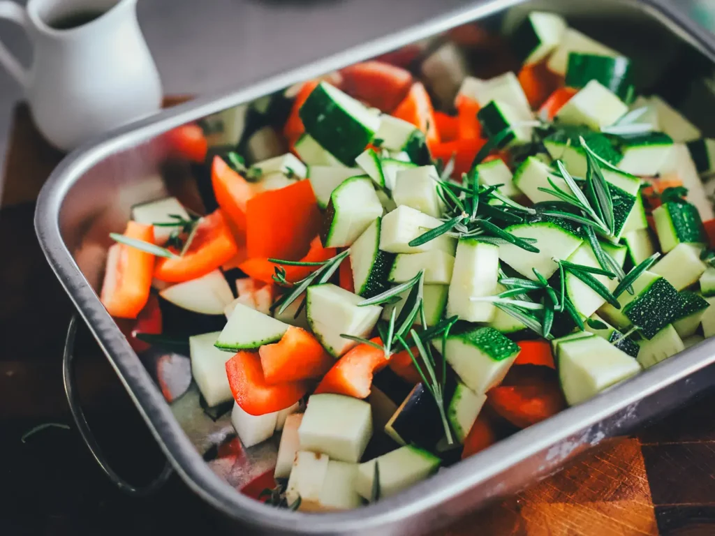 Gewürfelte Zucchini, Paprika und Aubergine mit frischem Rosmarin in einer Bratform