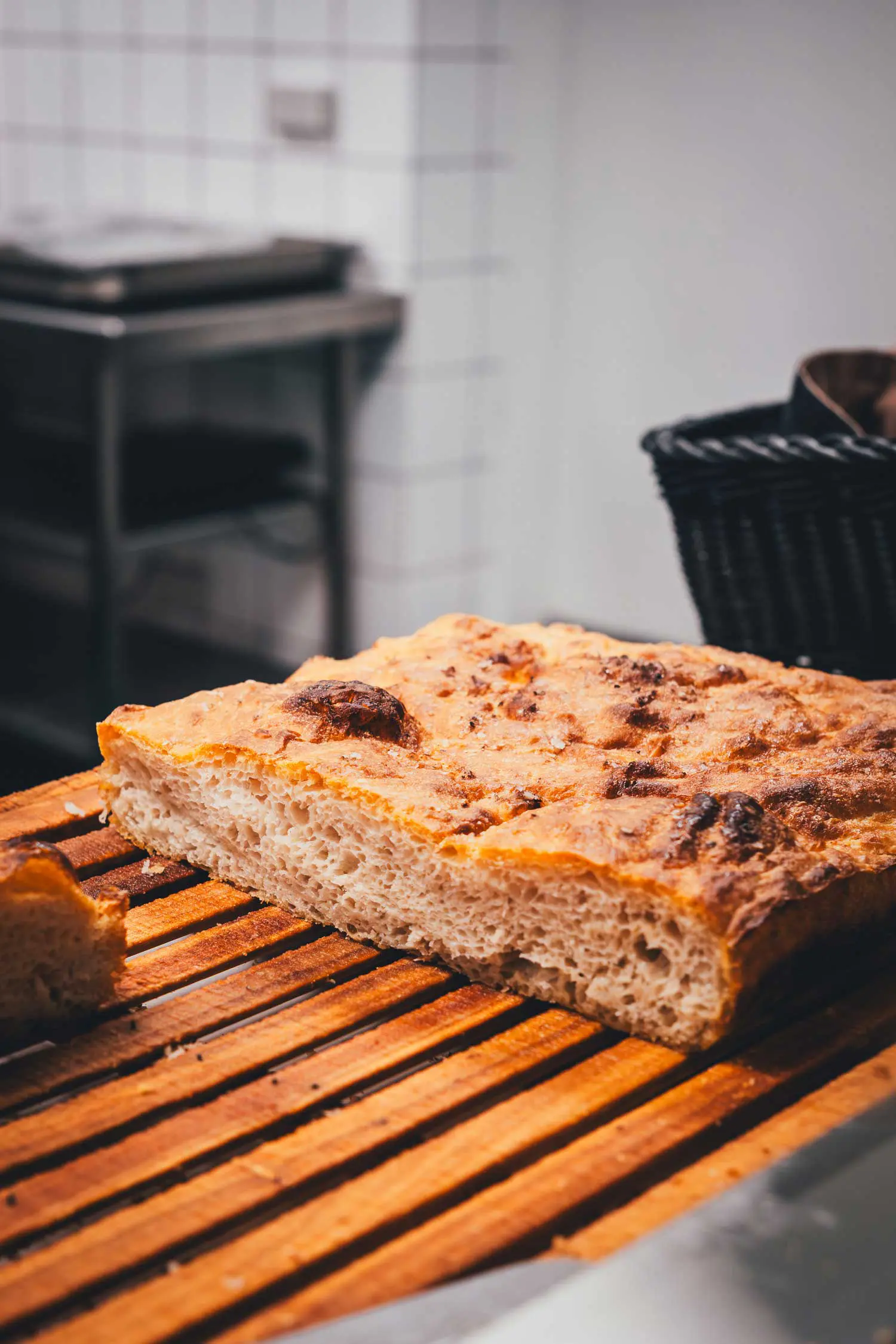 Angeschnittene Focaccia mit lockerer Porung und goldbrauner Kruste auf einem Holzbrett in der Küche