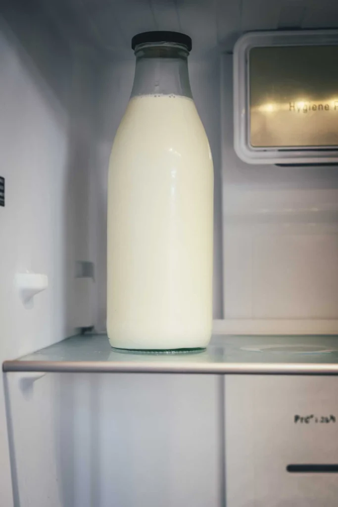 Glasflasche mit Rohmilch und schwarzem Deckel im Kühlschrank des Cafés von Svanholm
